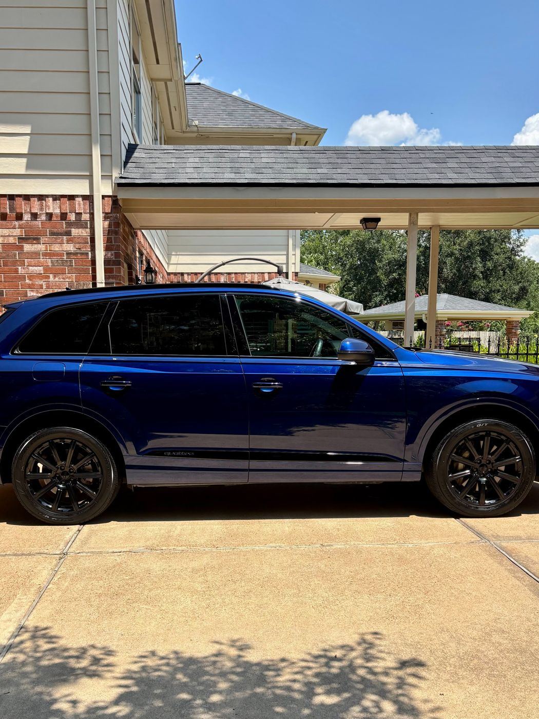 Side profile of a glossy blue Audi Q7 with black wheels after detailing