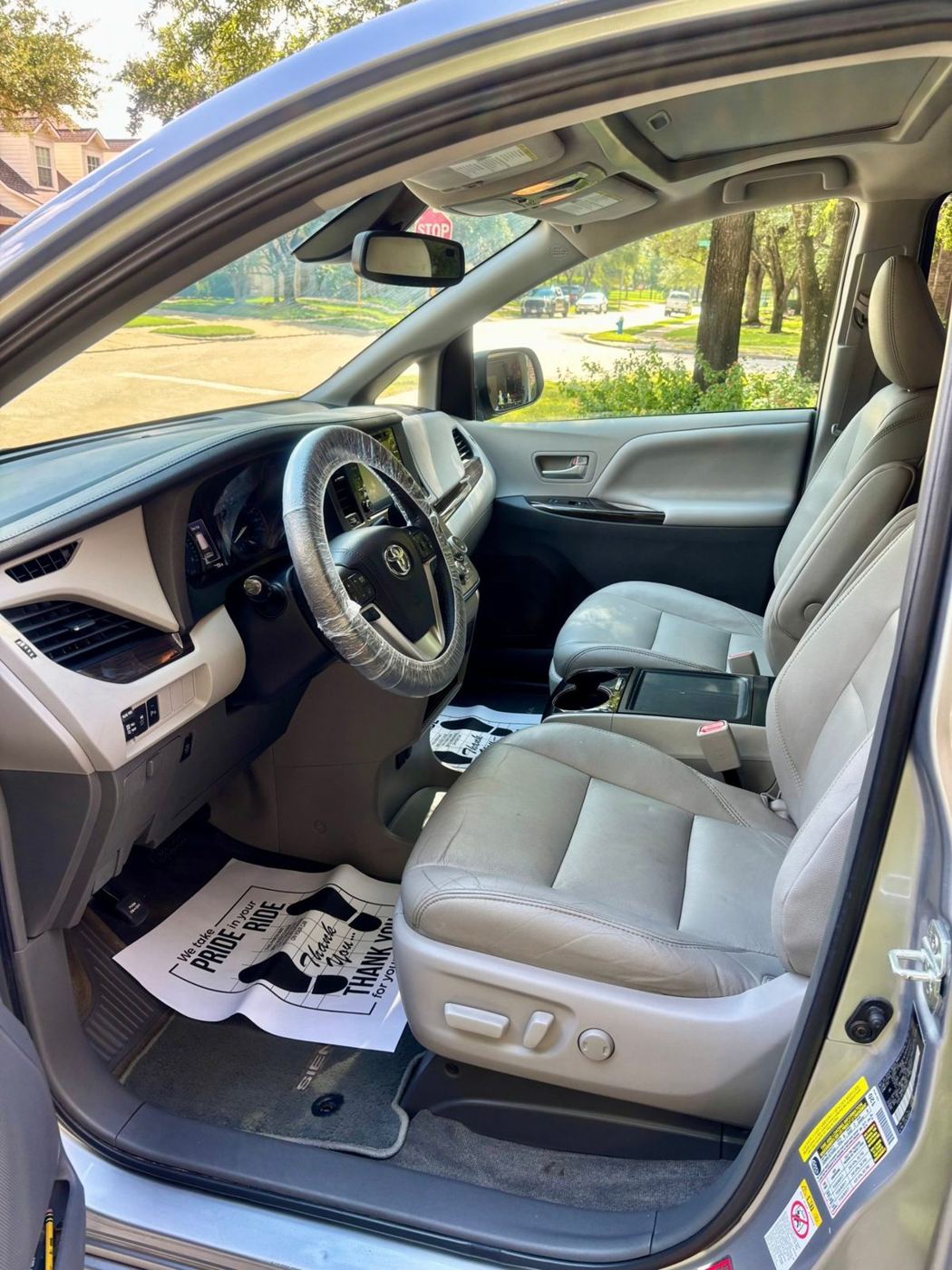 Clean light gray leather front seats and dash in a Toyota Sienna, with protective floor paper