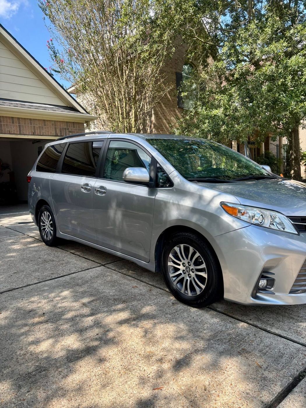 Freshly detailed silver Toyota Sienna in a driveway with glossy paint and dressed tires