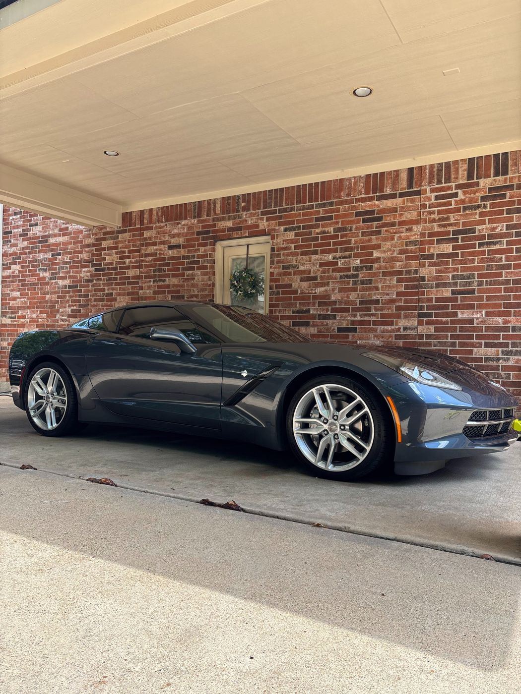 Side profile of a detailed gray Chevrolet Corvette with polished silver wheels