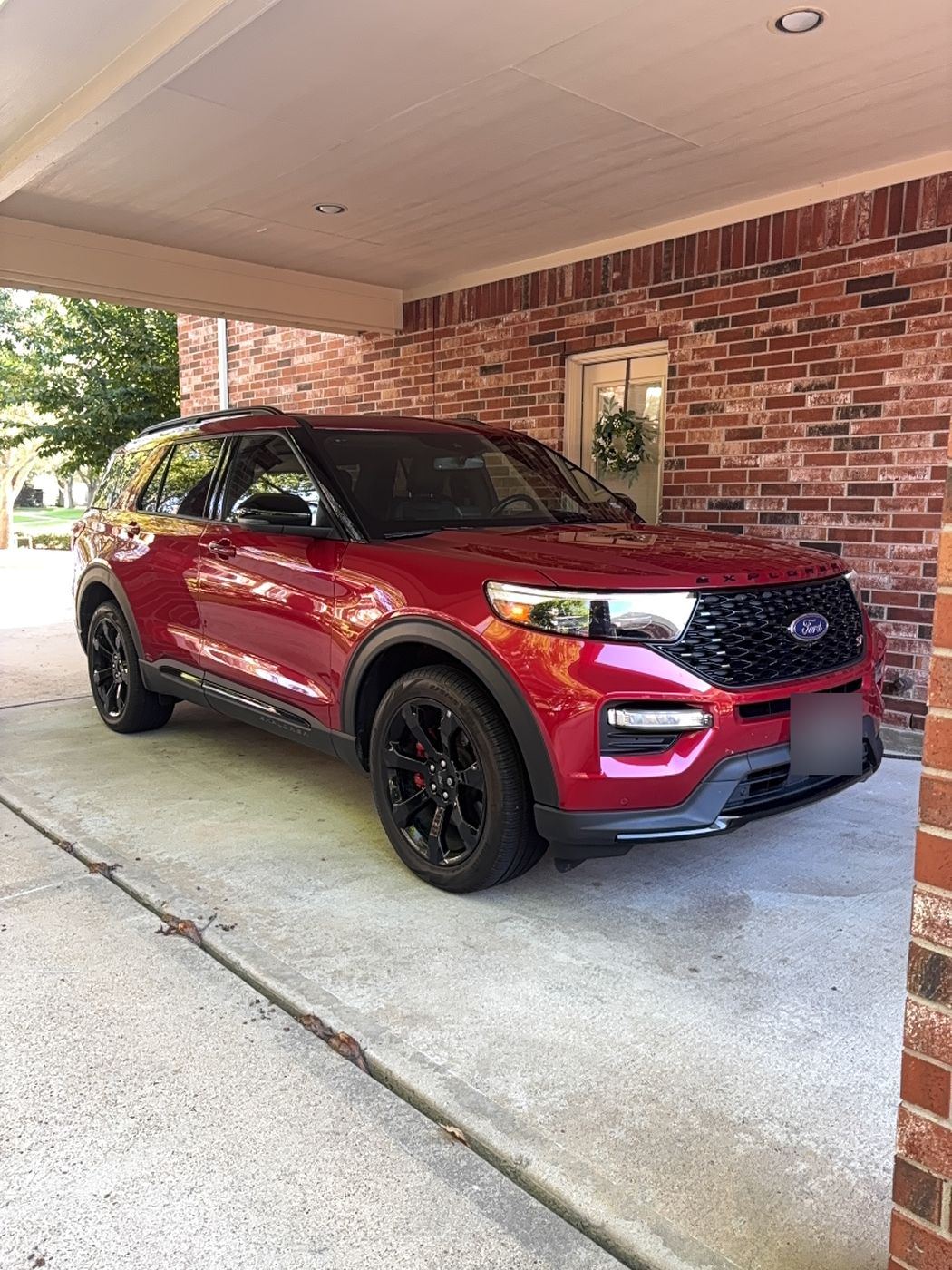 Glossy red Ford Explorer ST parked under a carport after detailing