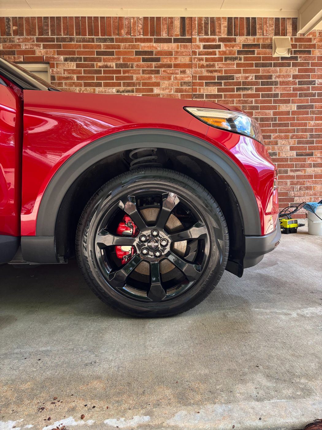 Clean gloss-black wheel and dressed tire on a red Ford Explorer ST