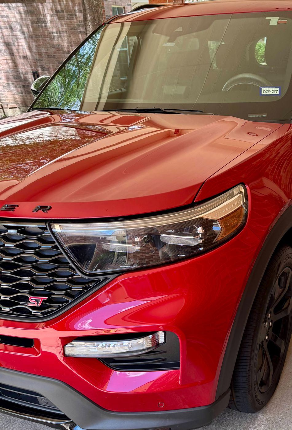 Close-up of the glossy red hood, headlight and grille of a Ford Explorer ST