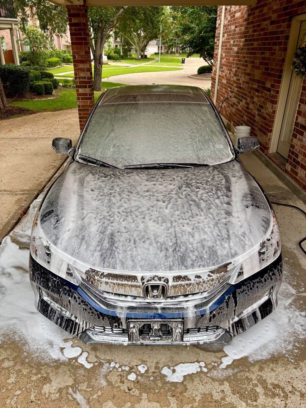 Honda Accord covered in foam during the pre-wash under a carport